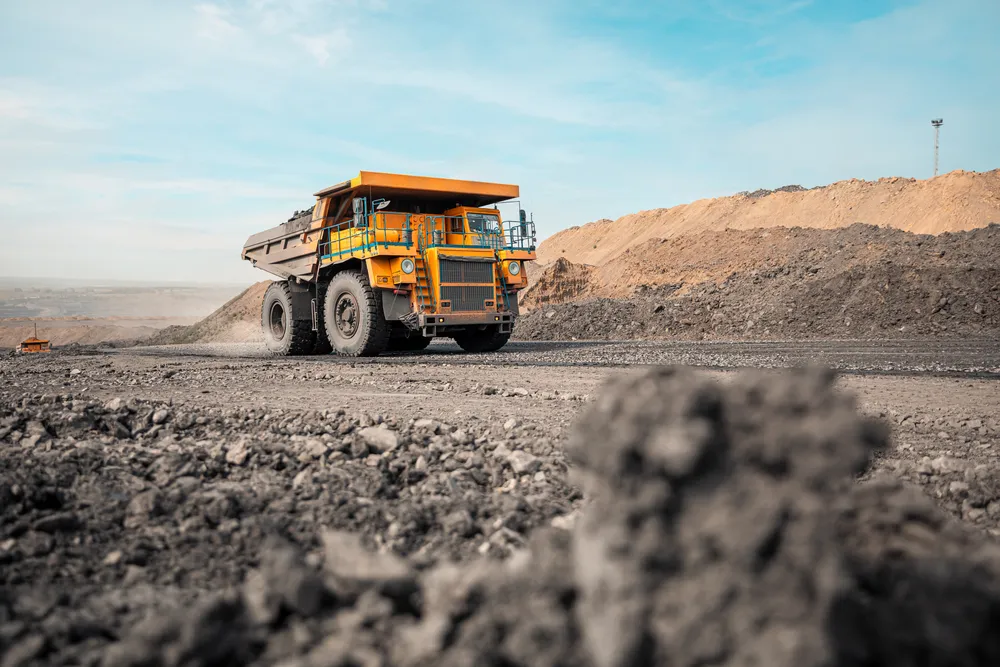  A large, yellow quarry dump truck at work, transporting materials at a mining site.